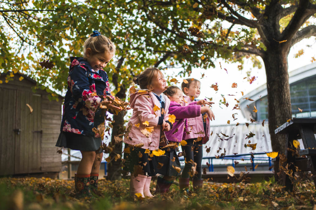 Nursery children throwing up autumn leaves Nursery children throwing up autumn leaves